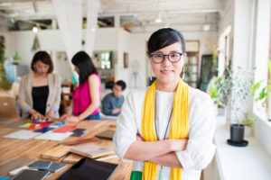 A woman in glasses is standing in front of a group of people.