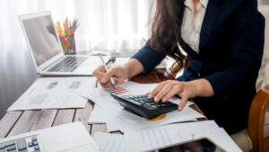 A woman in a suit is bookkeeping at her desk.