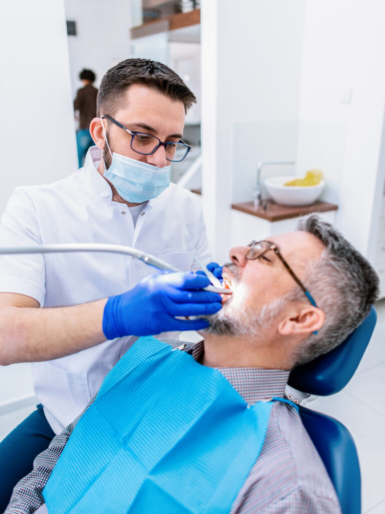 A business tax specialist near me with a male dentist examining a mature male patient in a dental clinic.