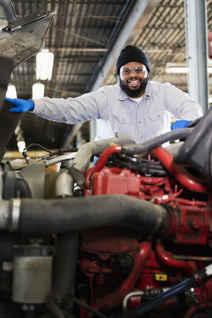 an accountant for small business clients, repairing a semi-truck, examining the engine, and smiling at the camera.