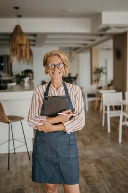 A woman in an apron providing accounting services for restaurants with a smile.