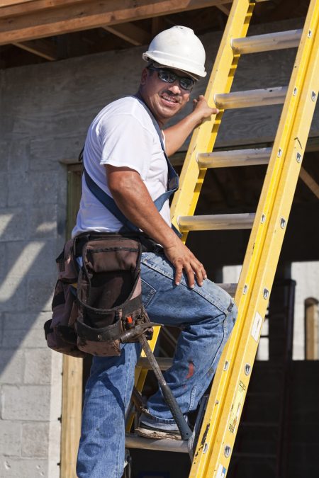 A man providing accounting services for construction companies while standing on a ladder.